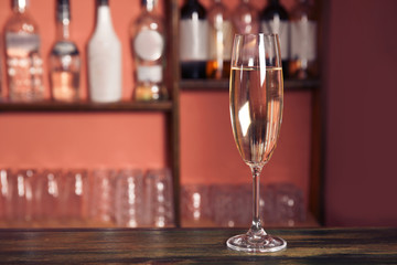 Glass of champagne on wooden counter in bar