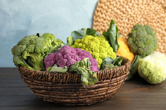 Wicker basket with different cabbages on wooden table. Healthy food