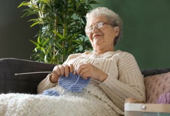 Senior woman knitting warm sock at home