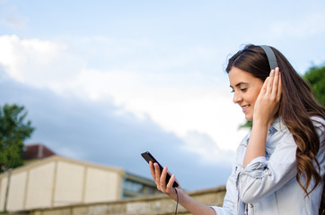 Pretty young girl with long hair looking at her phone while browsing music.