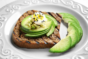 Tasty toast with avocado on plate, closeup