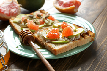 Plate with tasty toasts on wooden background
