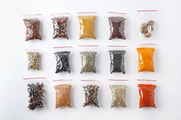 Poster Plastic bags with different spices on white background, top view © New Africa