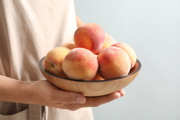 Woman holding plate with fresh sweet peaches, closeup