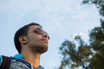 head shot of man wearing sunglasses looking into the distance in front of trees and sky - 214148243