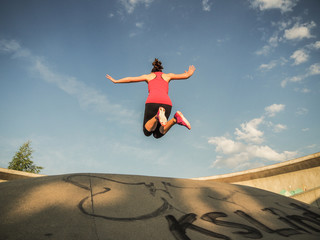 jumping Fitness WOMAN WITH arms up from frog view and blue cloudy sky in the background