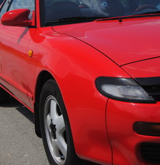 Vista de carro desportivo, frente e lateral de um carro desportivo vermelho com far&oacute;is escamote&aacute;veis