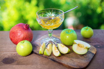 Honey and apples on wooden table over bokeh garden background