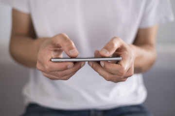 Young man using a touchscreen smartphone horizontally - Hands close-up 