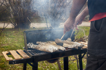 Fish in aluminium foil fried on the grill outdoor