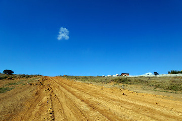 Estrada de terra em aclive  com ceu azul limpo ao fundo 