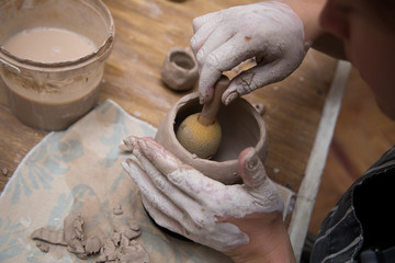 Woman working with clay with her hands close up at a pottery workshop