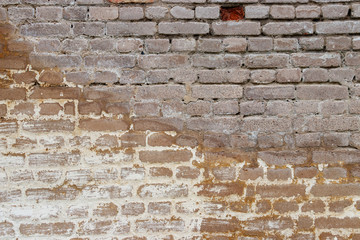 Background of a red brick wall partially repaired with plaster. Part of the brick wall is destroyed.