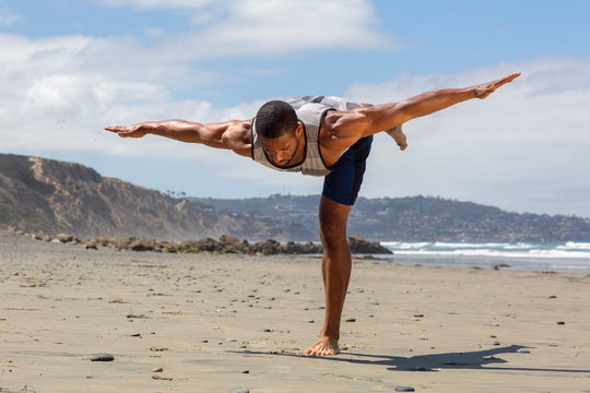 Athletic man at the beach in Warrior lll yoga pose