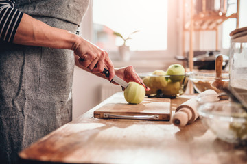Woman cutting apples in the kitchen - obrazy, fototapety, plakaty