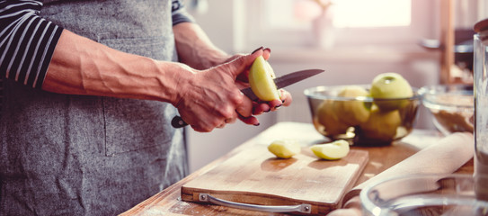 Woman cutting apples in the kitchen - obrazy, fototapety, plakaty