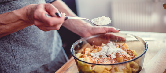 Woman making apple pie and adding spice