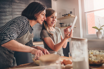 Mother and daughter searching apple pie recipe on the tablet