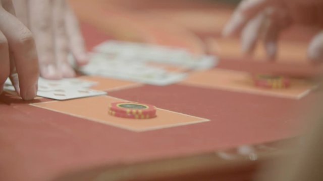 Slow motion shot of cards and chips on velvet poker table in casino. Gambling, luck and addiction concept.