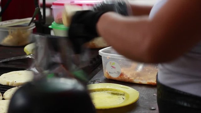 Close up of woman stuffing arepas with shredded chicken