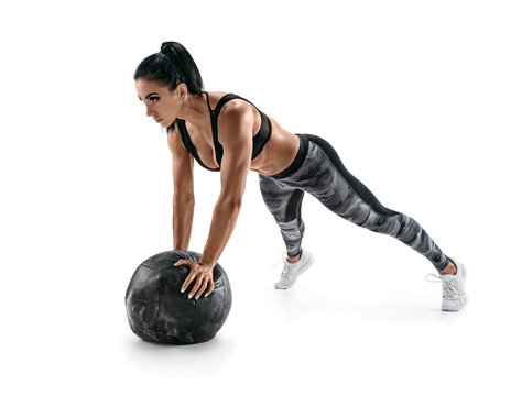Sporty latin woman doing push ups on med ball. Photo of woman in military sportswear isolated on white background. Strength and motivation