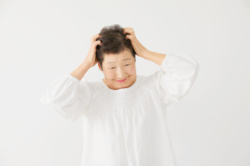 女性　お年寄り　頭を抱える
