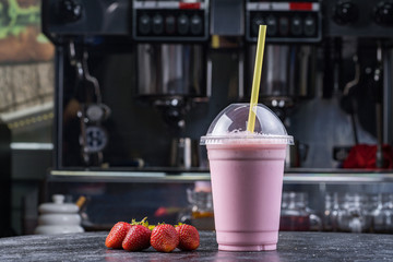 Strawberry milk shake to take away with straw on a dark background