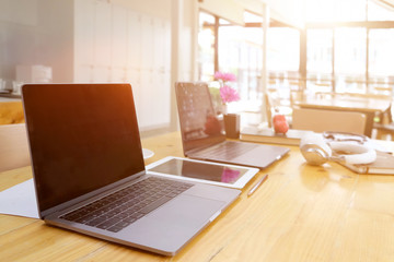 Sideview of office desktop with blank laptop and various office tools on wood desk.