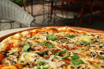 Vegetarian pizza with onions, pepers olives and cheese, restaurant atmosphere