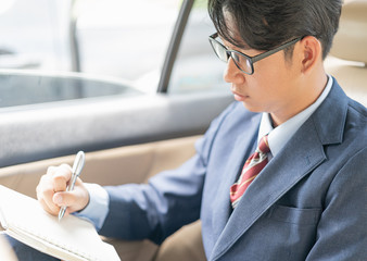 Businessman working in the backseat of a car