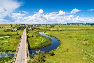 Foto auf Acrylglas Luftbild Aerial view of the windy river, concrete bridge, and fields with beautiful cloudy sky