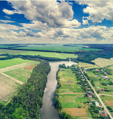 Fototapeta premium Aerial view of countryside and river with a beautiful sky. Forest and village along the river