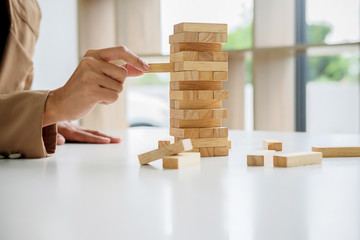 Hand of business people planning, risk and strategy in business.Businessman gambling placing wooden block on a tower.