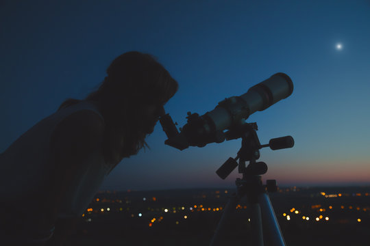 Girl looking through a telescope at the stars.