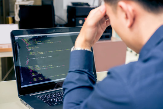 Overworked young man at front of laptop having headache programming and coding technologies