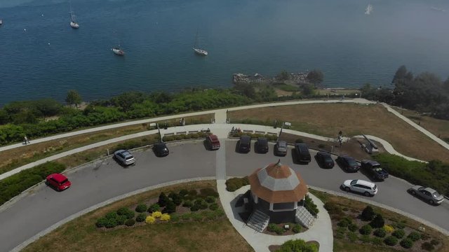 An aerial view of Fort Allen Park in Portland, Maine on a summer foggy day. Tilt up to boats on the Fore River harbor in the distance.  	