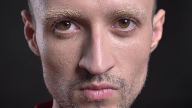 Blond man hipster is watching at camera, nodding haed, black background