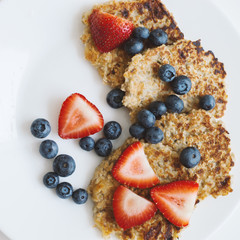 Whole grain pancakes with strawberry and blueberry on white plate. Oat pancakes with no added sugar. Healthy breakfast meal