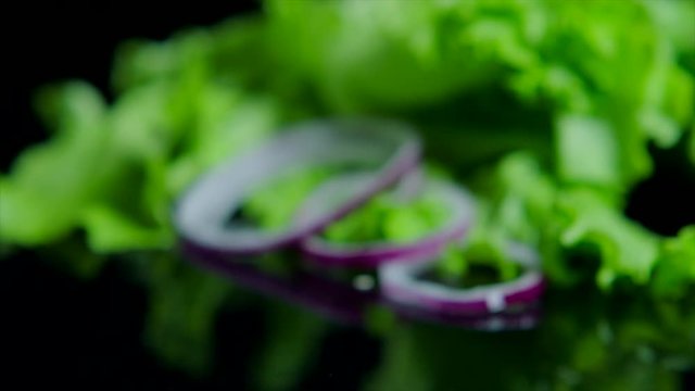Close up of fresh vegetables and tasty burger with cheese and beef cutlets on the black background