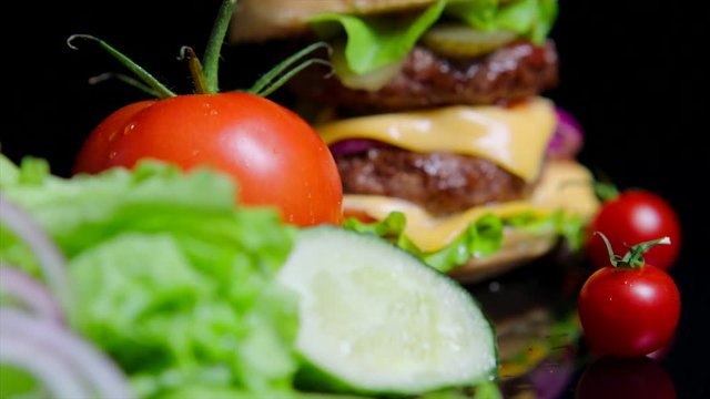 Close up of fresh greens and delicious burger. Black background for commercial use