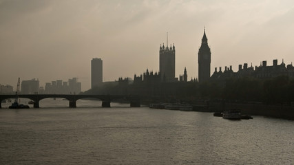 Westminster bridge over river Thames, with Big Ben silhouette in background, cloudy backlight haze.