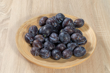 Top view on a wooden basket full of ripe plums