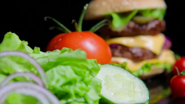 Close up of fresh greens and delicious burger. Black background for commercial use
