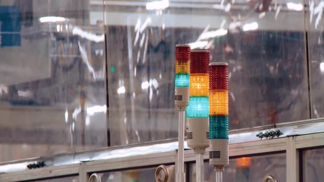 Lamps on the factory line are lit with different colors, signaling the beginning of the next stage of production. The picture goes into defocus