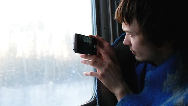 man in a rug travels by train and takes pictures of nature on the phone, the camera shows the view from the window, nature through the train window, 4k.