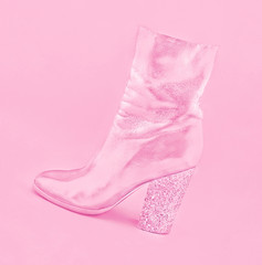 Stylish pink women's leather shoe with heel made of confetti on pastel background.