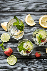 delicious cold summer cocktail with mint, strawberries and kiwi in glasses on wooden table