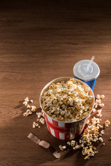 close up view of paper bucket with popcorn, soda drink and retro cinema tickets on wooden tabletop