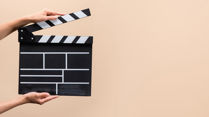 partial view of woman holding clapper board in hands isolated on beige
