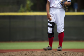 close up of baseball players legs with red stockings standing on first base